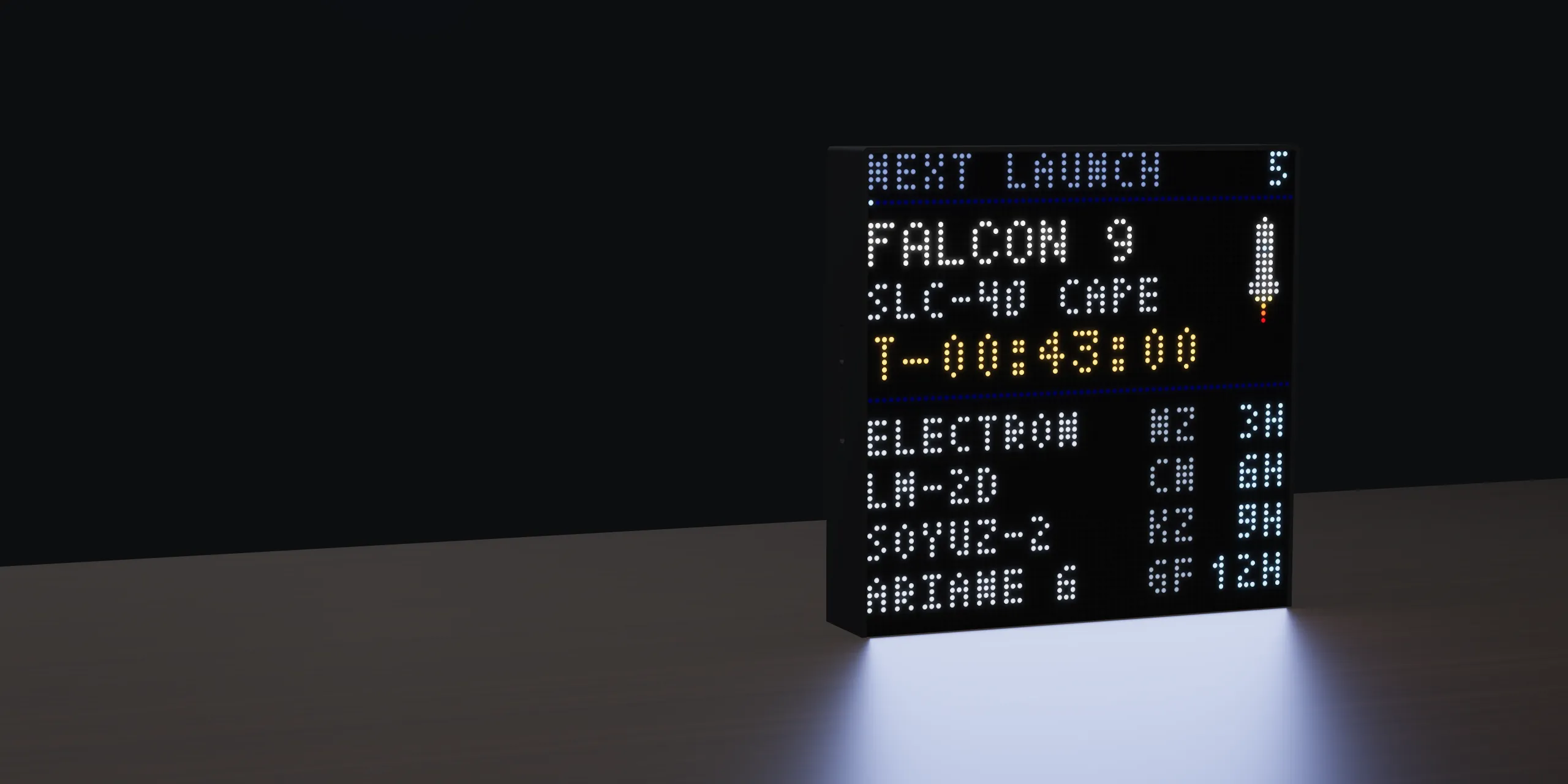 High Above on a dark desk, its panel showing a Falcon 9 countdown and the next four launches